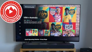 A TV with a BBC iPlayer menu on screen showing the USA vs Australia World Cup match. A logo with a mountain reads "Adventures in AV".