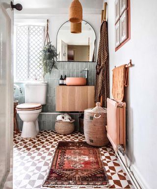A small bathroom idea with stencil floor design, Turkish vintage rug, ikea wall unit, concrete planter sink, arched mirror and shutters