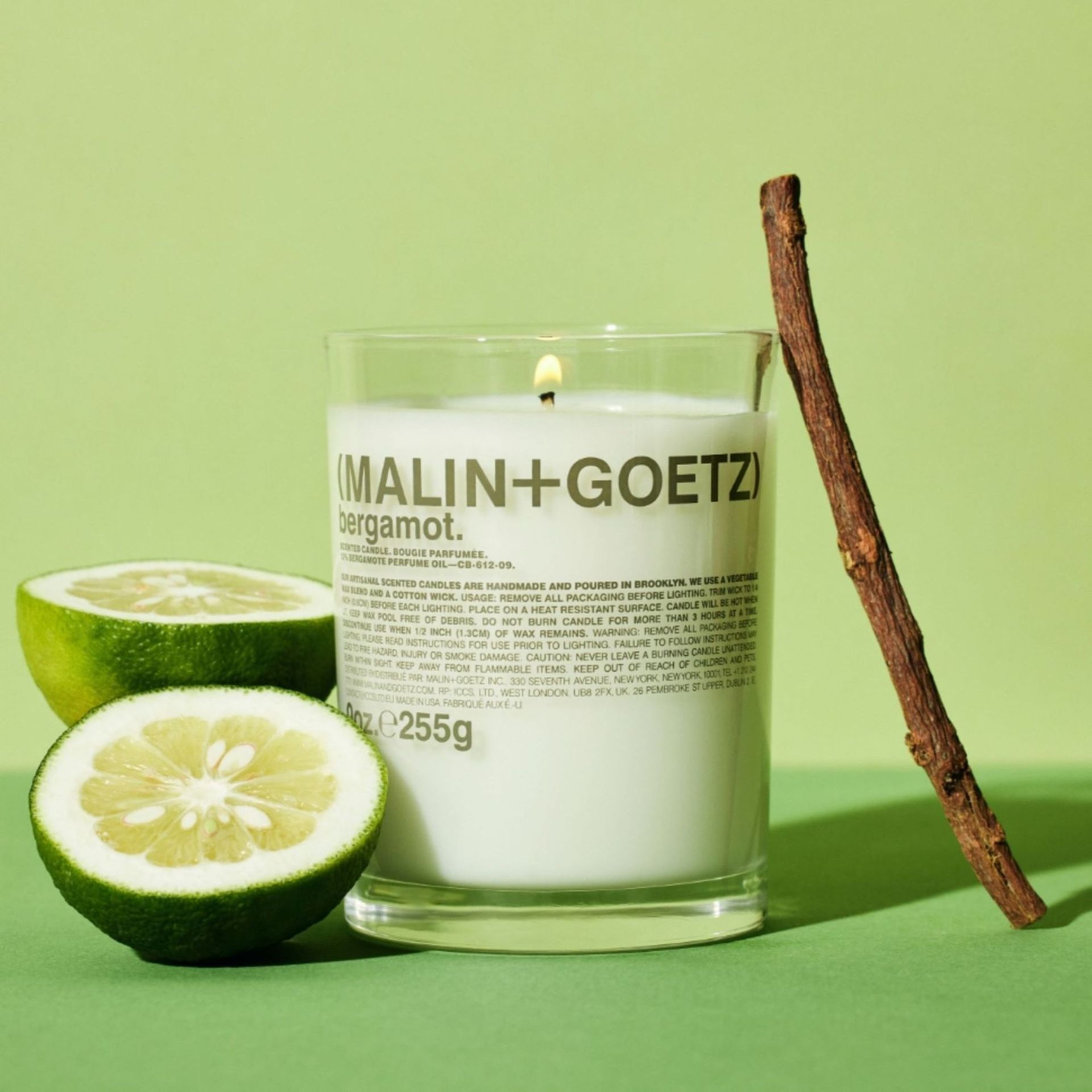 MALIN+GOETZ Bergamot Candle against a green background.