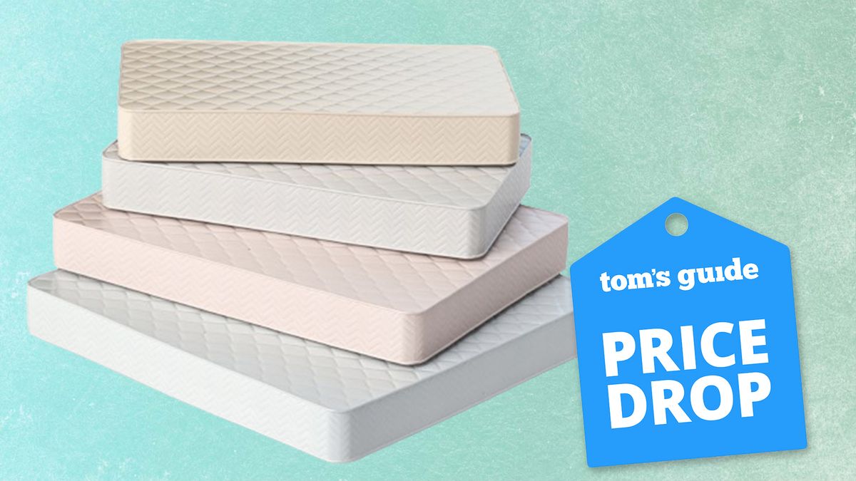 A pile of white hybrid and memory foam mattresses on sale this Labor Day placed on a green background with a blue price drop badge overlaid on the image