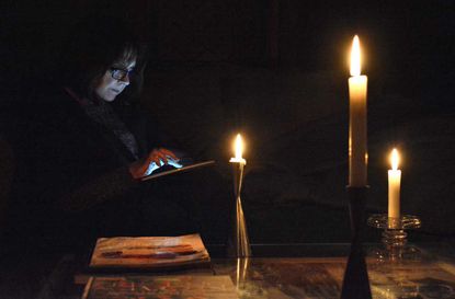 photo person reading by candlelight during blackout