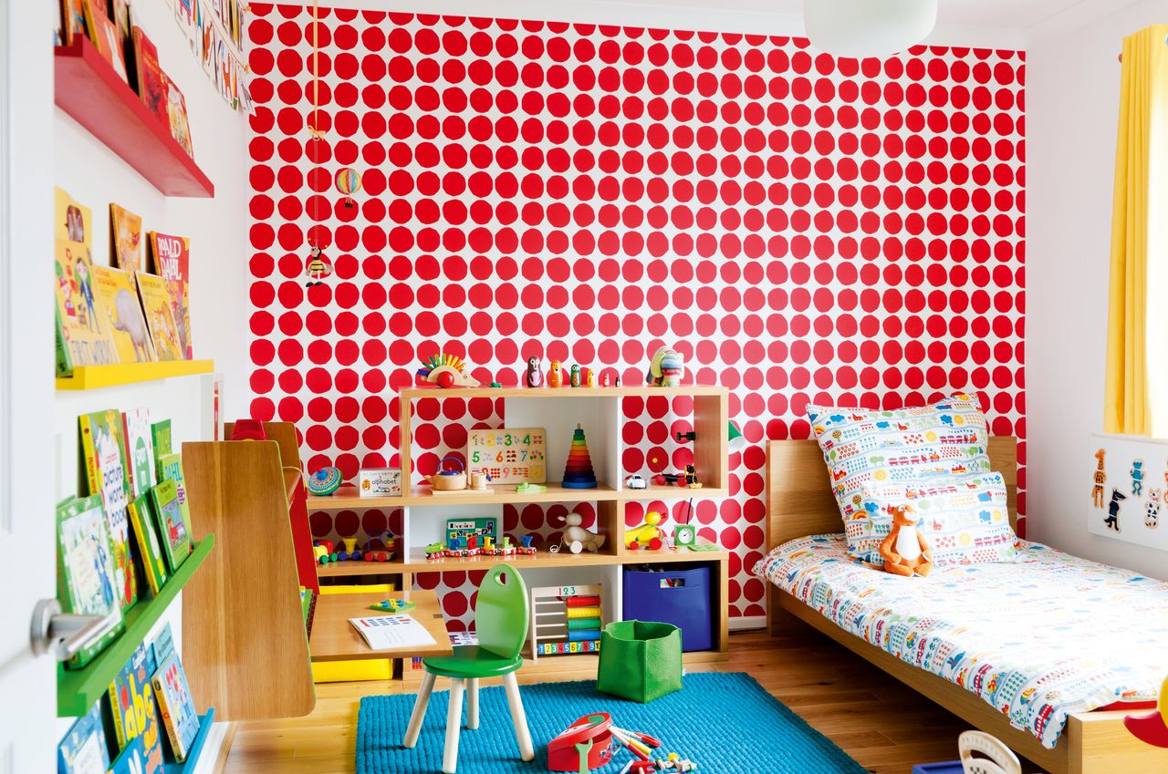 Child&#039;s room with red spotty wallpaper and a wall-hung desk