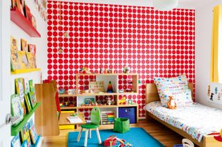 Child's room with red spotty wallpaper and a wall-hung desk