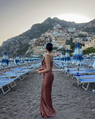 Amalfi coast shopping picks: @kristincabat wears a silk evening dress on a beach in Italy