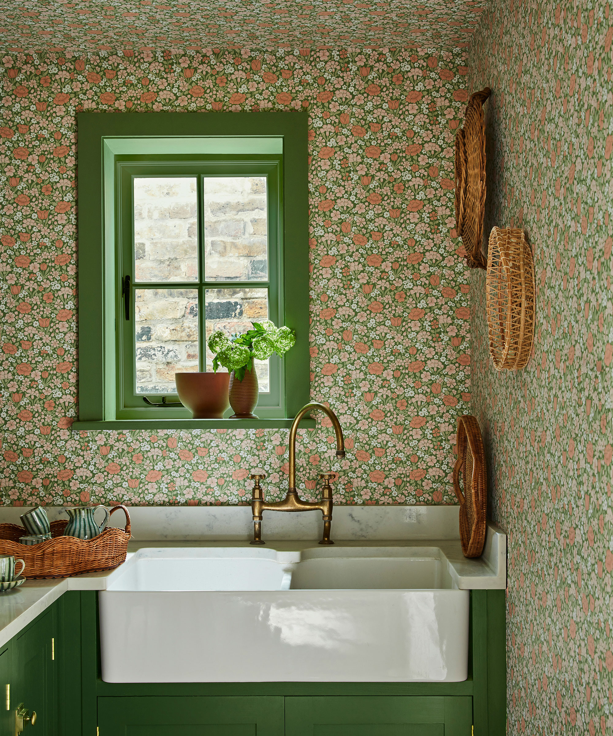 small utility room with ditsy floral wallpaper and green units and window
