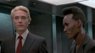 Christoper Walken and Grace Jones standing together in a conference room in A View To A Kill.