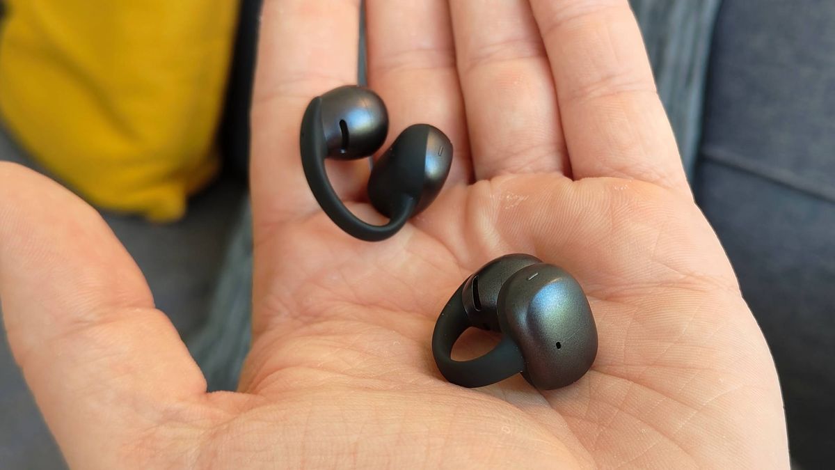 The Shokz OpenDots Air earbuds in a man's hand.