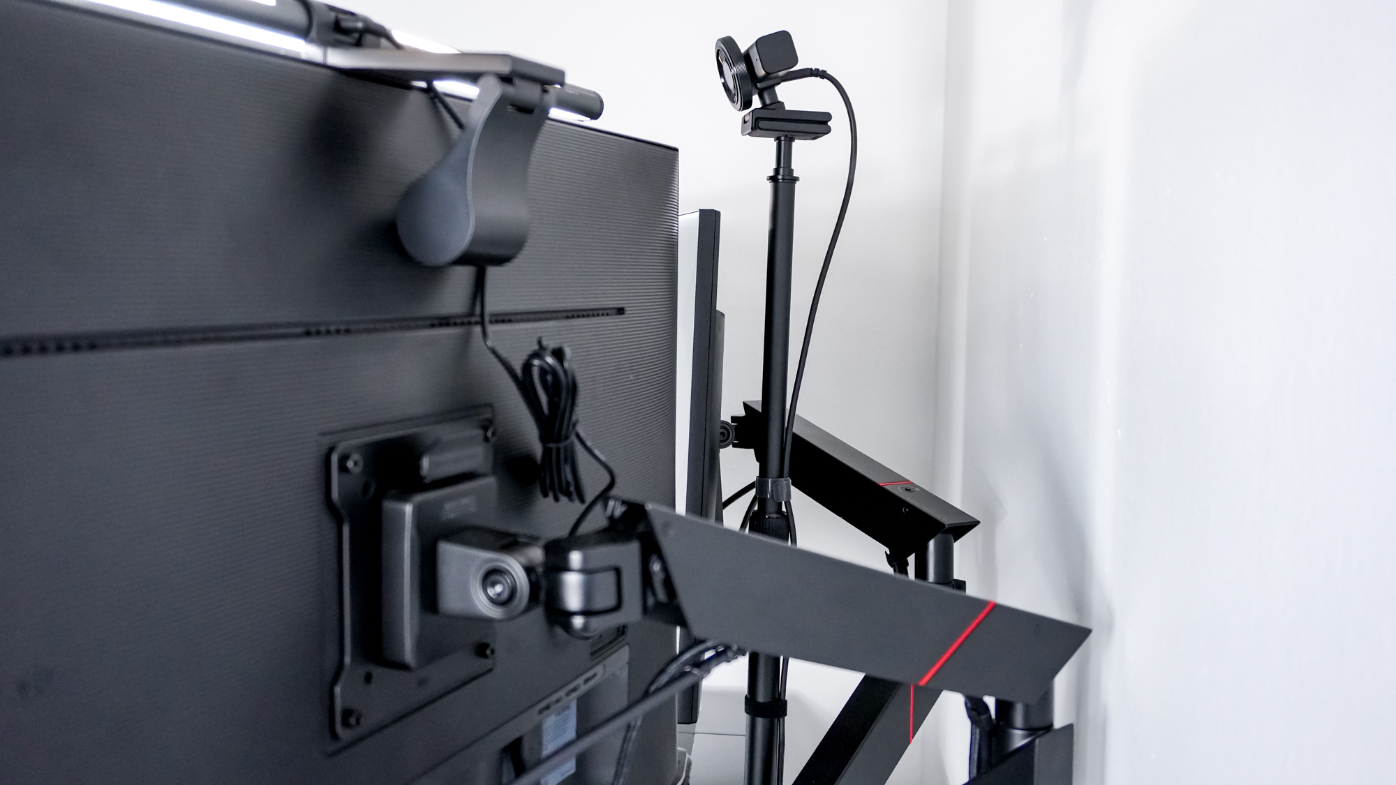 A rear view shot of a webcam mounted on the SmallRig Camera Desk Mount behind a dual-monitor setup