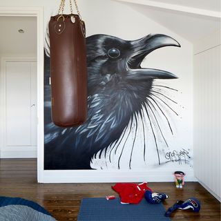 room with white wall bird painting on wall brown punching bag and wooden flooring
