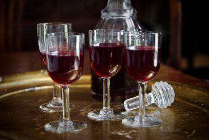Six small glasses of redcurrant gin with a decanter