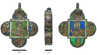 Here we see the back, side and front of a palm-size medieval pendant shaped like a four-petaled flower. The pendant has green and blue on it.