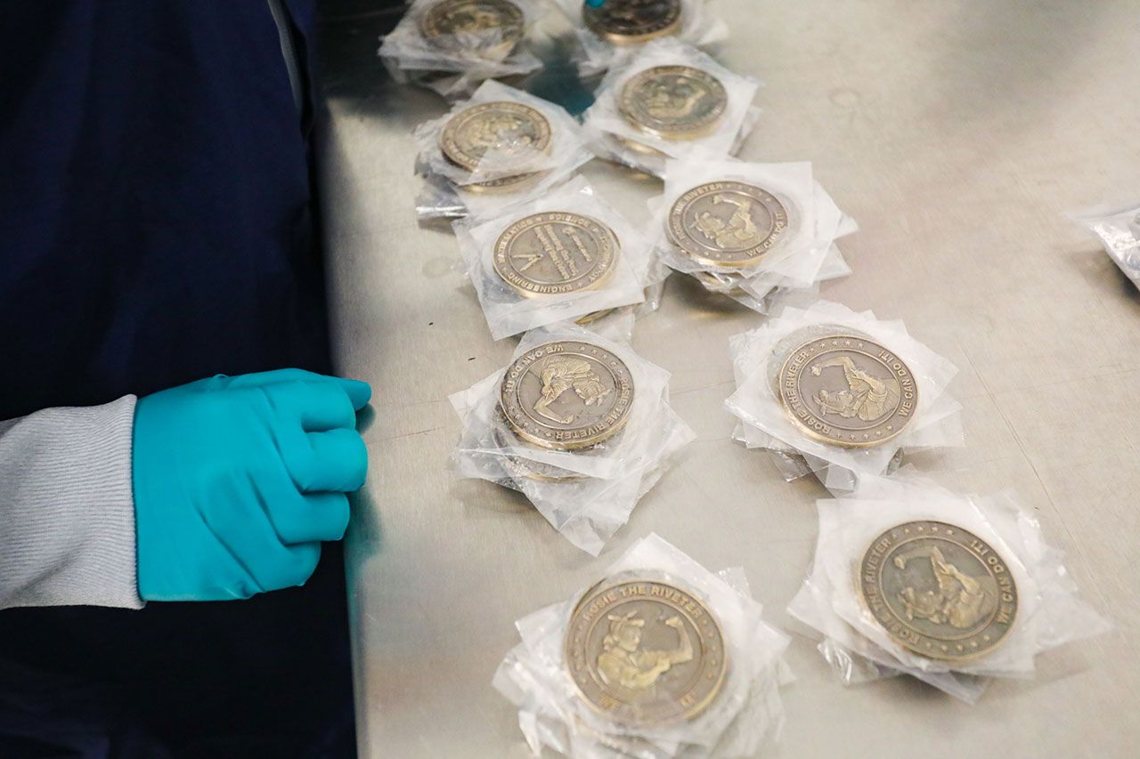 Rosie the Riveter commemorative coins are prepared for their flight on the second orbital flight test of Boeing's Starliner.