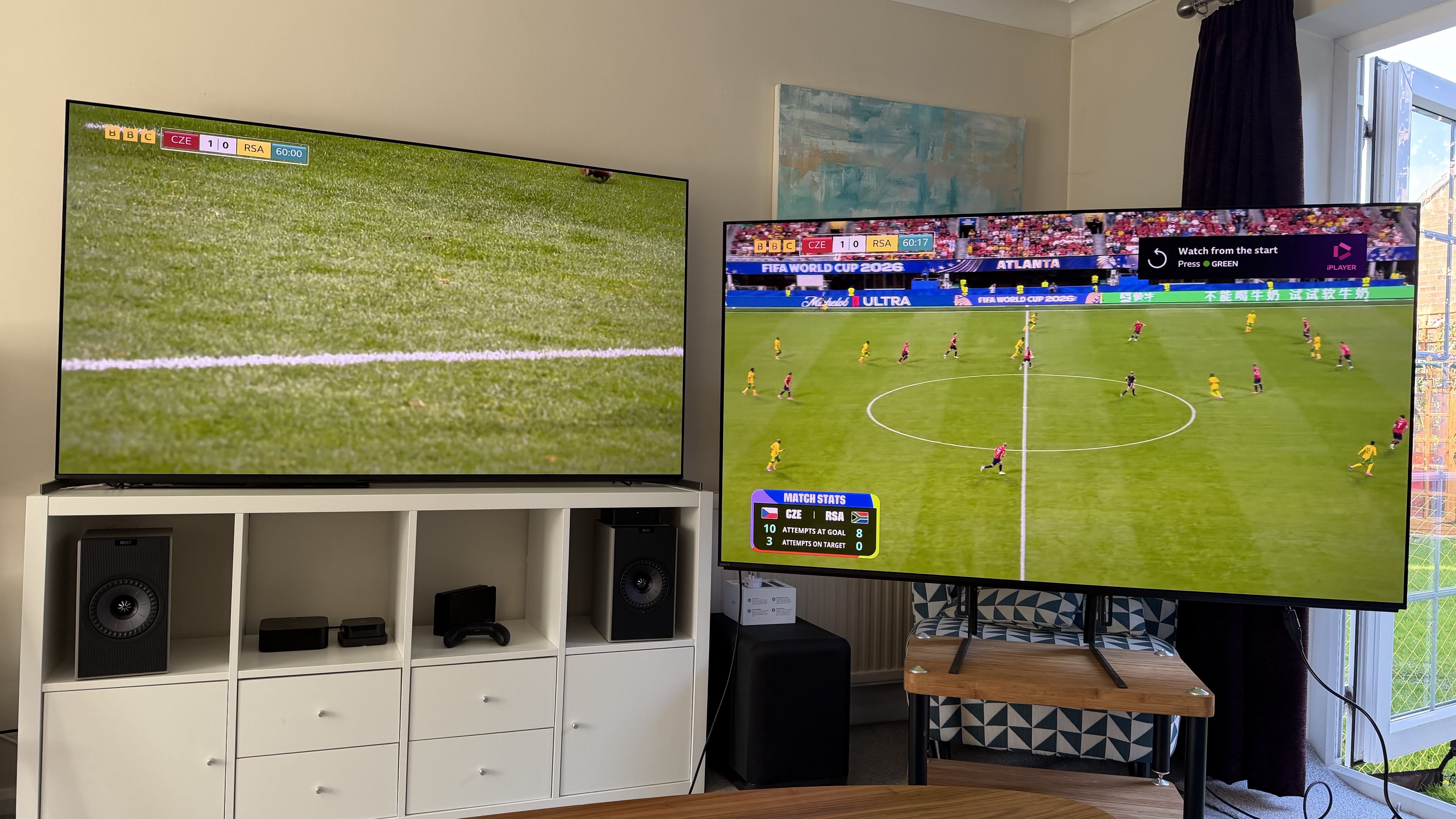 Two 65-inch TVs showing football, pictured in a living room
