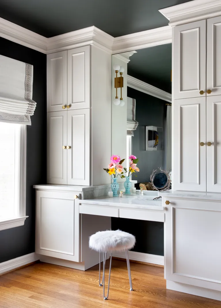 A bedroom with a small stool by the mirror