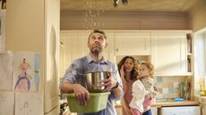 Two parents and a child look up at the ceiling where water is dripping.