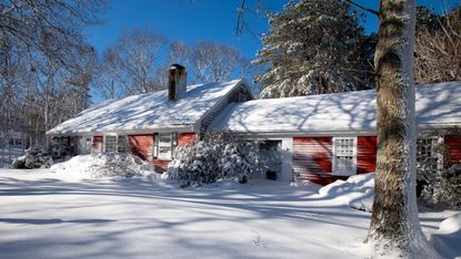 cape cod house in winter with snow covered garden