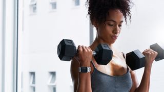 Woman performs biceps curl exercise with dumbbells