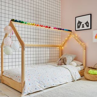 Kids room with wooden bed, grid wallpaper and fairy lights