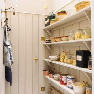 Cream painted walk-in kitchen pantry with open shelving