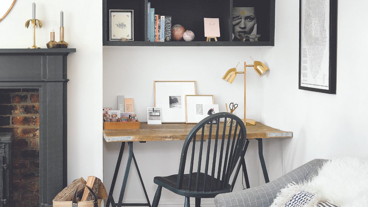 A home office in a living room alcove with the black chair matching the fireplace and storage unit mopunted on the wall above the desk