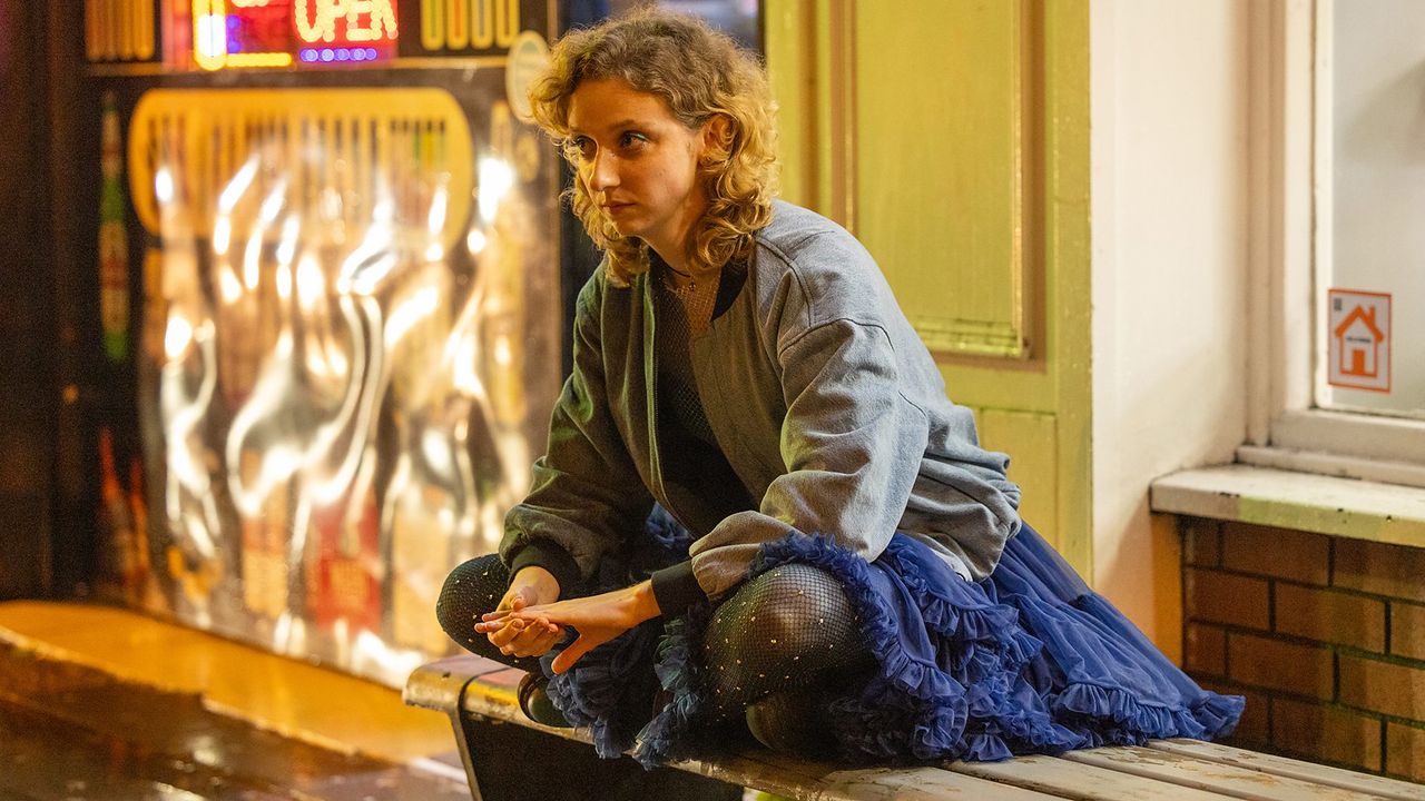 Emily Fairn as Casey, wearing a hoodie and skirt