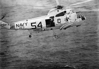 U.S. Navy helicopter crewmembers assist the Apollo 9 astronauts during recovery operations just after splashdown. Astronaut James A. McDivitt, mission commander, is in the Billy Pugh net about to aboard a Sikorsky SH-3D Sea King