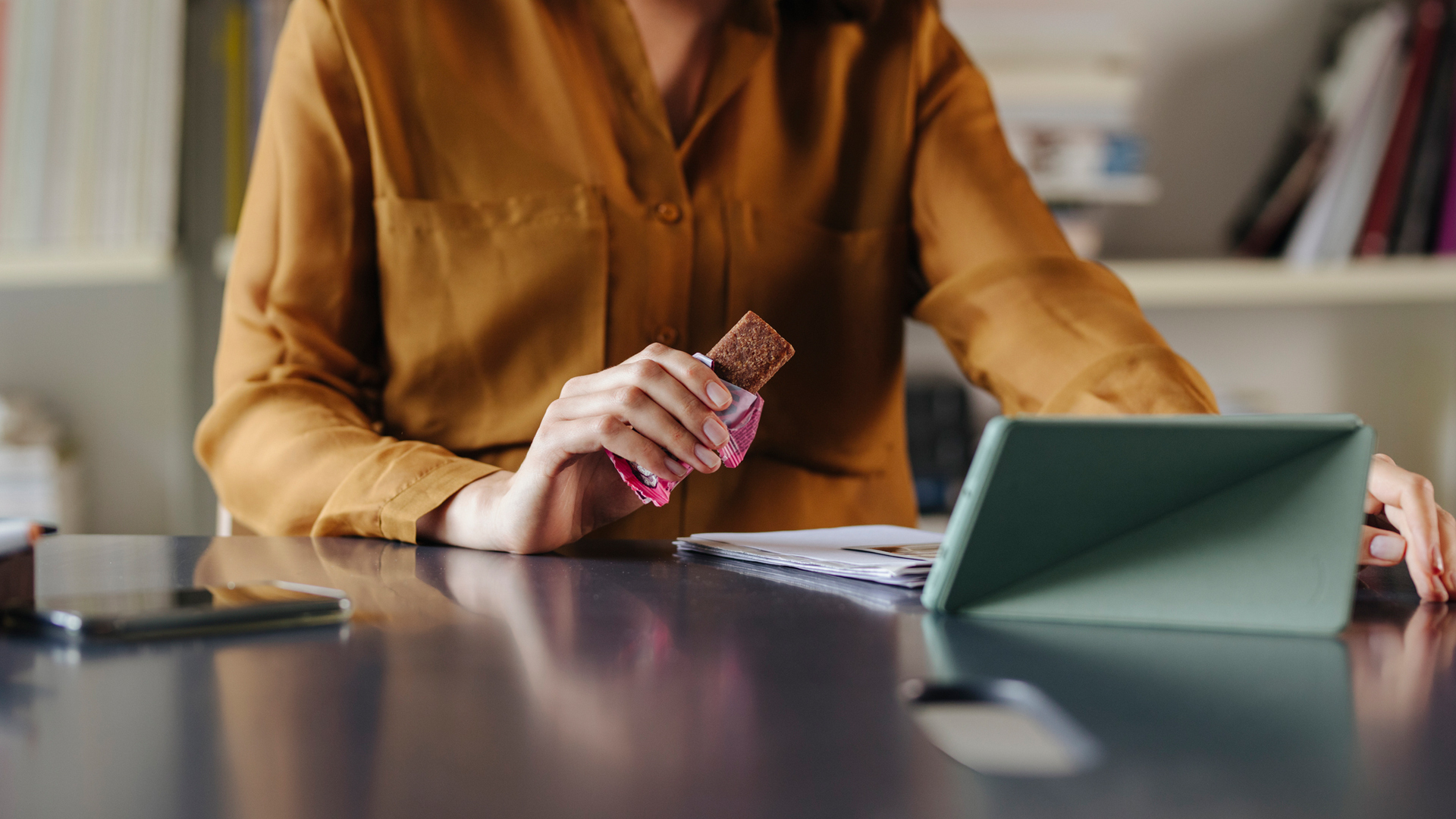 woman eating a protein bar at her desk