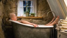 still image from Nancy Meyer's movie 'The Holiday' of actress Cameron Diaz in a tiny claw foot bathtub in a bathroom with stone walls and a sloped ceiling