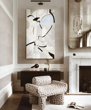 neutral living room with patterned chair, marble fireplace, large mirror and statement artwork