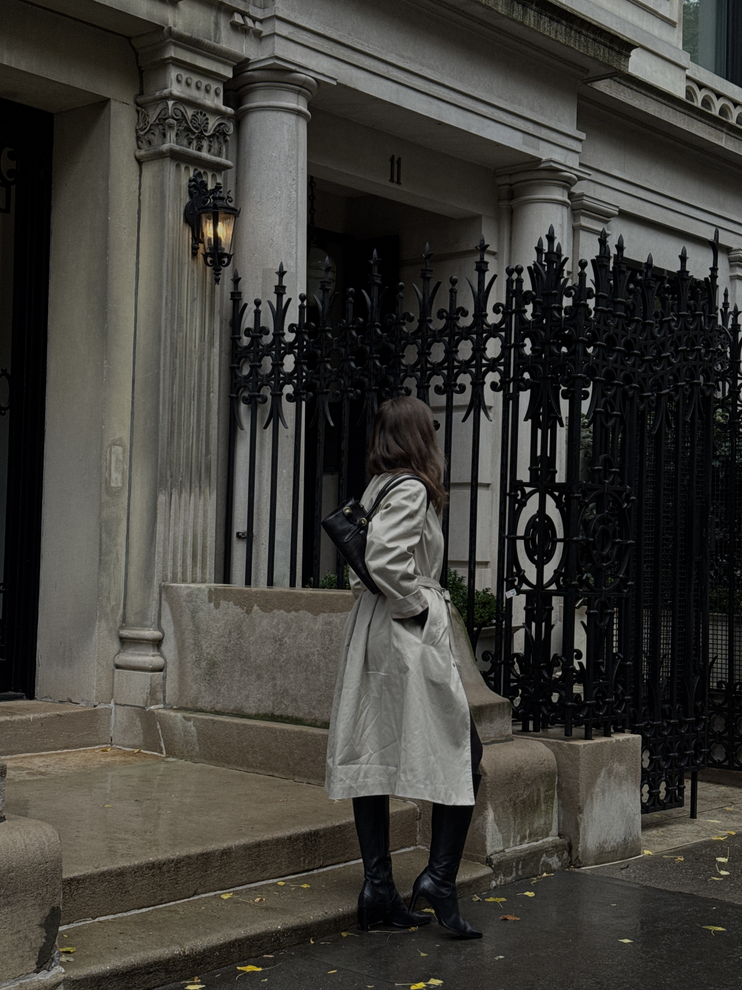 Kathryn Zahorak looking away in a trench coat in black boots
