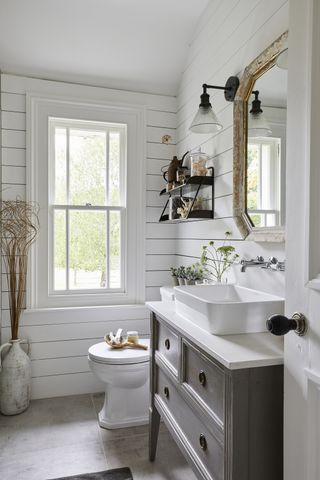 white powder room with shiplap walls, grey vanity unit, shelving