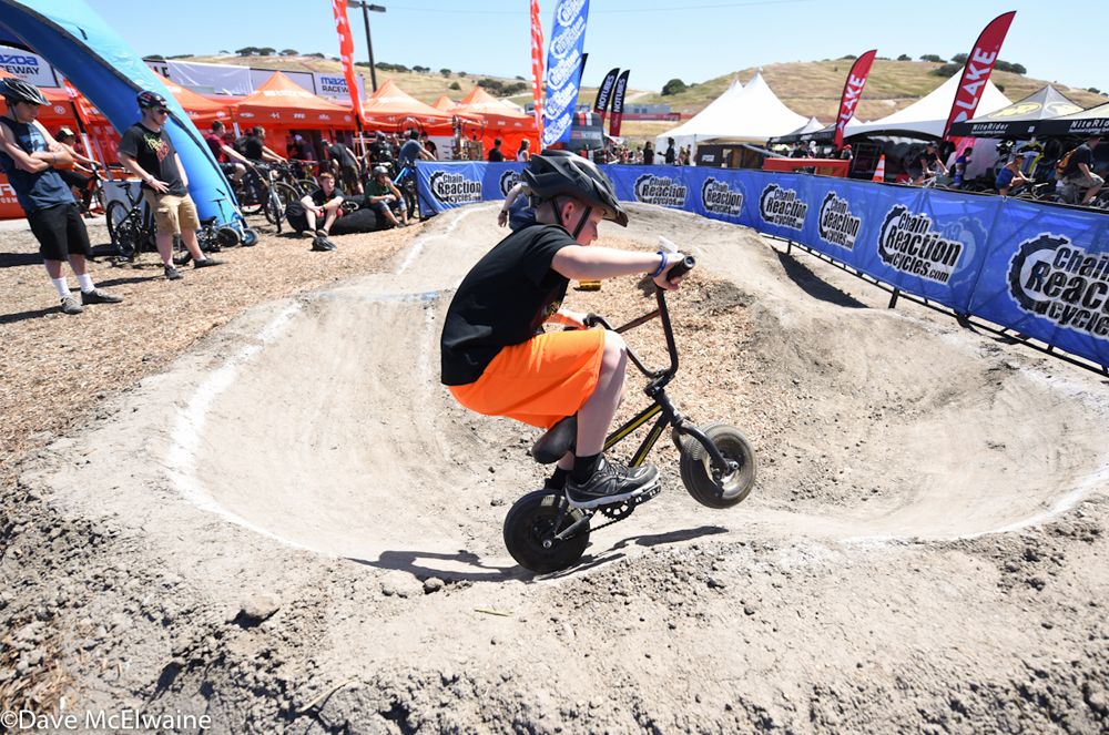 A young rider does tricks on a pump track while the race was going on