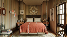 Characterful, striped bedroom featuring a four-poster canopy bed styled with bordered pillow cases and a vintage-inspired textured terracotta bed blanket.