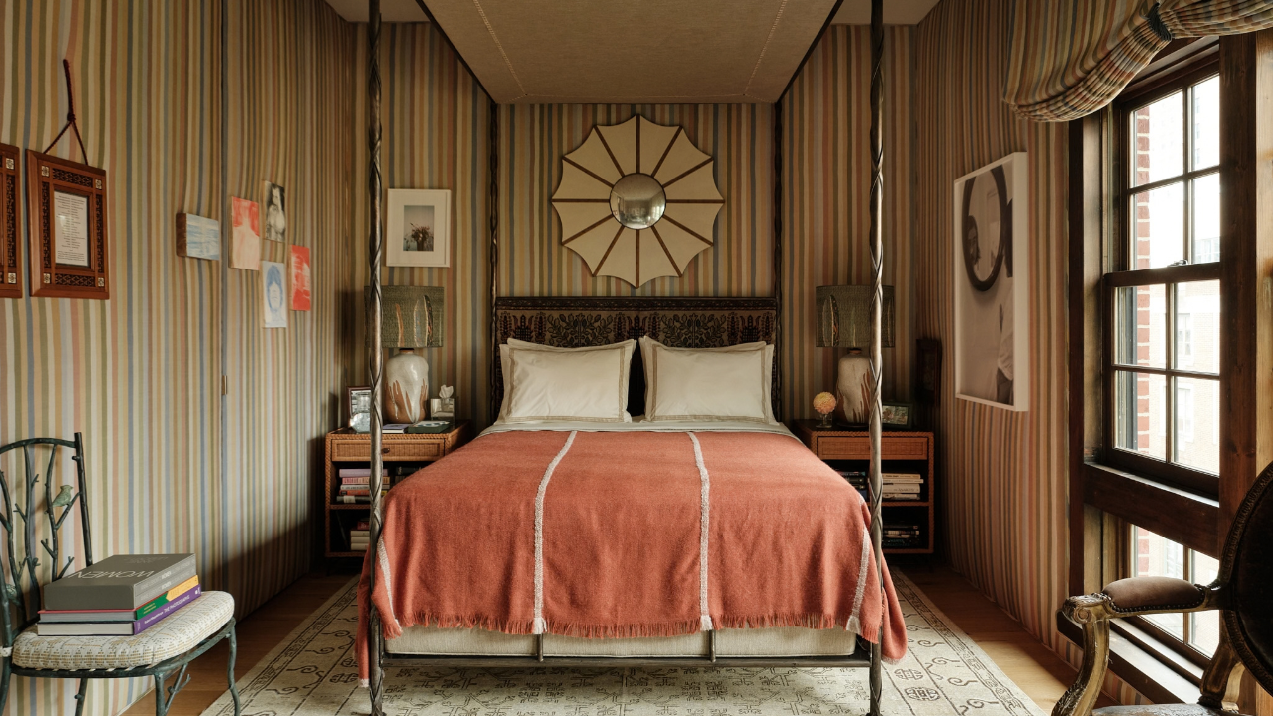 Characterful, striped bedroom featuring a four-poster canopy bed styled with bordered pillow cases and a vintage-inspired textured terracotta bed blanket.