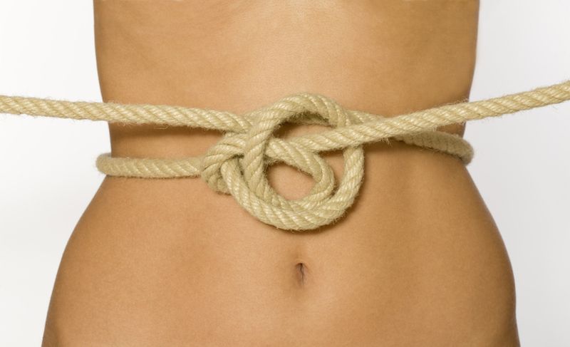 A woman&#039;s abdomen shown with a knotted rope in front