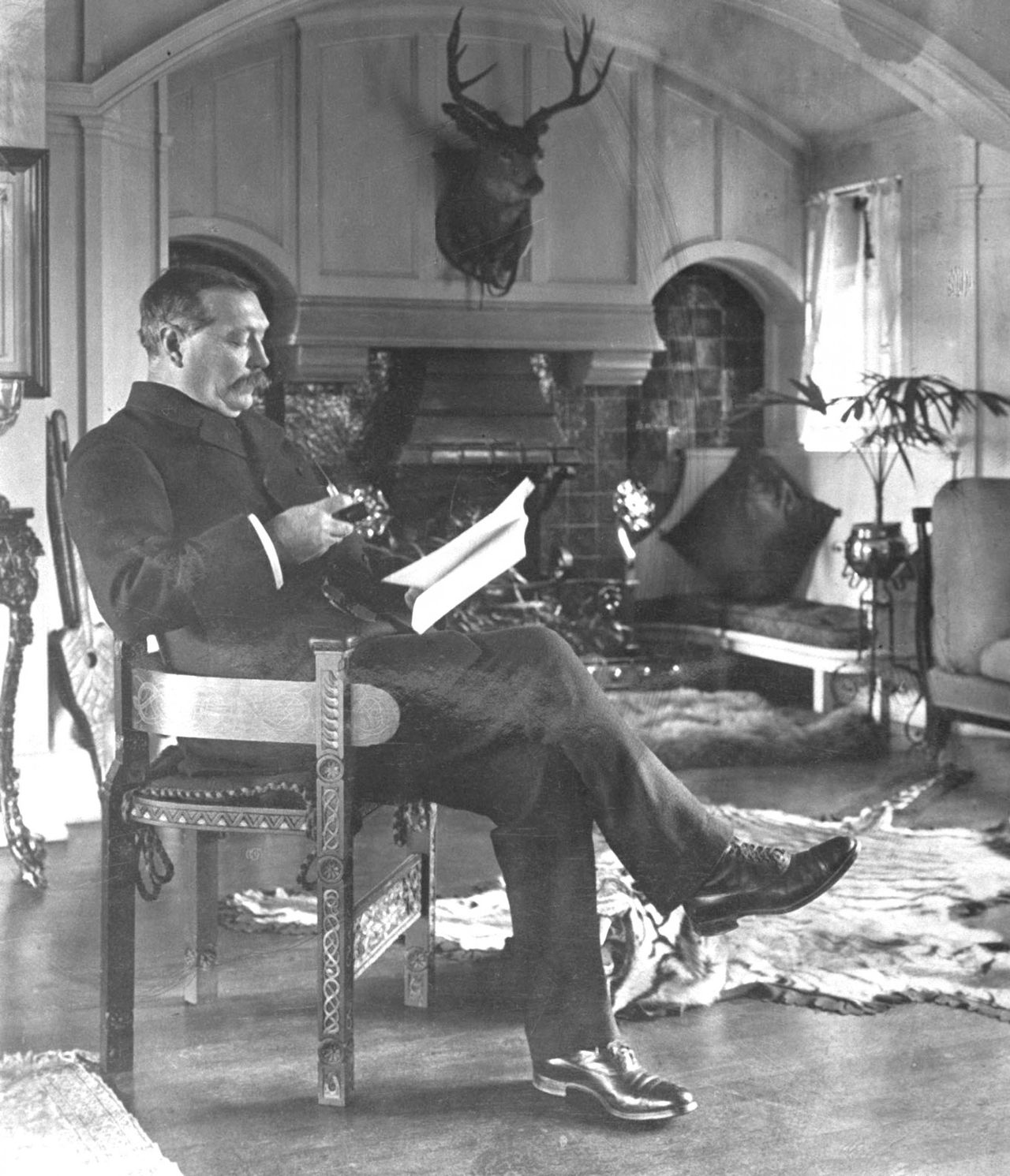 Sir Arthur Conan Doyle seated reading in the Music Room of Undershaw, his home in Hindhead, Surrey. Photographed by E. O. Hoppe/Mansell/The LIFE Picture Collection via Getty Images.