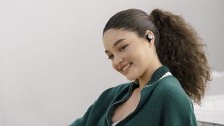 a smiling woman wearing a pair of true wireless earbuds