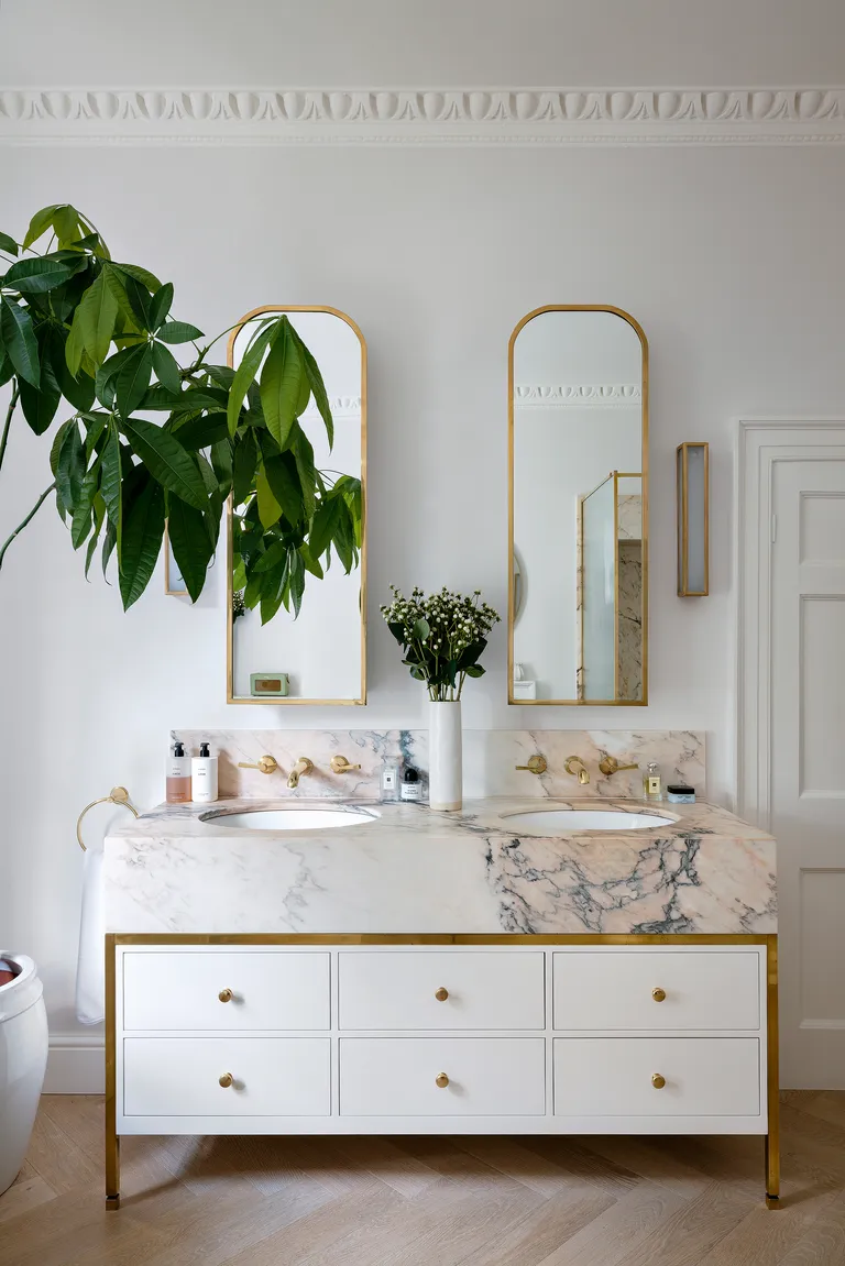 Double sink in a bathroom with a veined marble vanity unit and house palnt