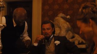 Leonardo DiCaprio laughing while holding a glass of liquor as Samuel L. Jackson looks down at him in Django Unchained