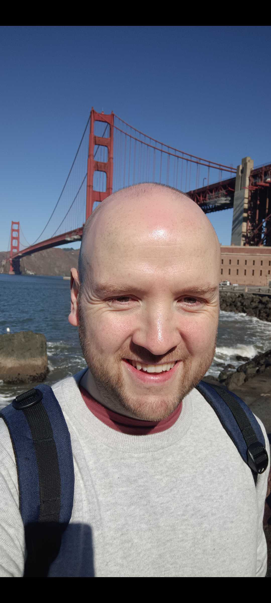 Will Cotter, COO of HappyCleans, standing in sunshine in front of San Francisco Bridge.