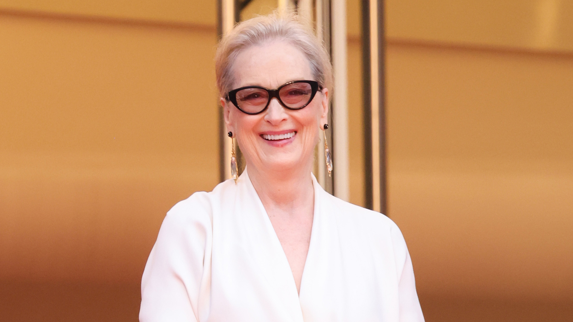 Meryl streep wearing glasses and an all white outfit.