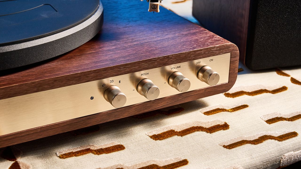 Crosley C65 turntable and bookshelf speakers photographed in front of a blue background on a brown table.