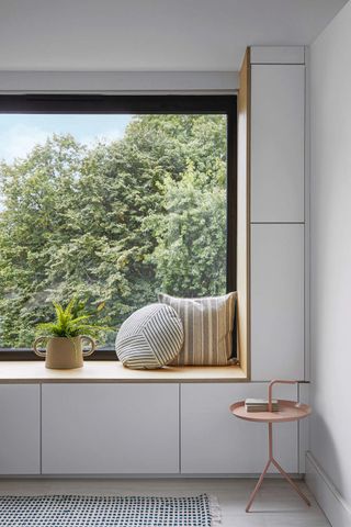 A picture window out onto the garden, with a wide window seat and storage cupboard. The pared-down Scandi-inspired remodelled and renovated family home