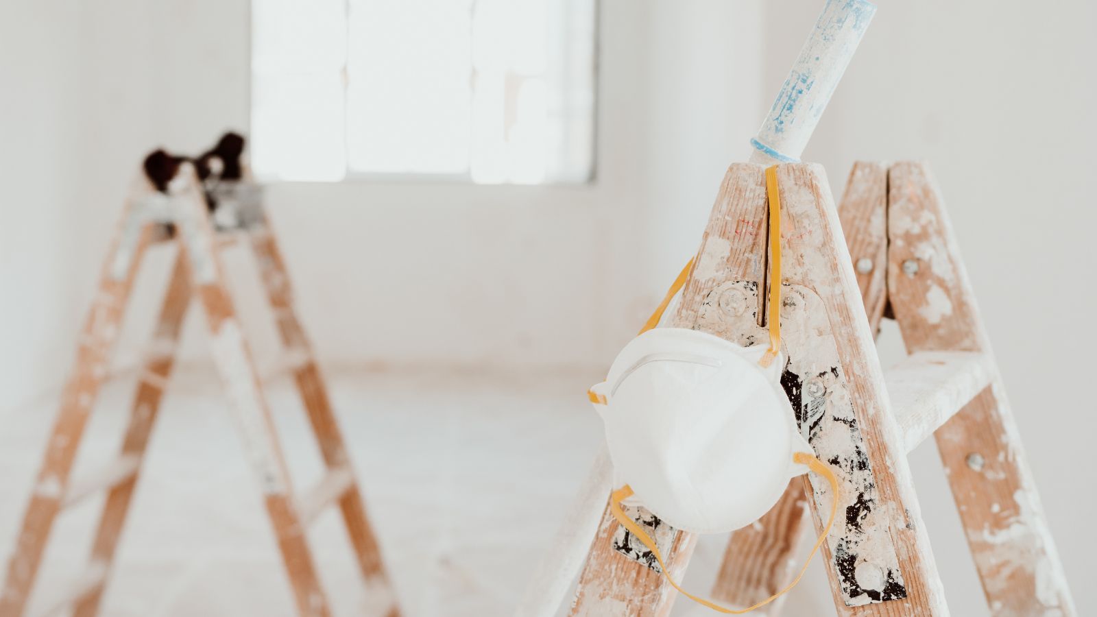 Ladders and painter tools on white room at construction site.
