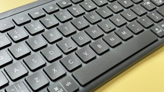 The Logitech Signature Slim K950 wireless keyboard against a yellow background.