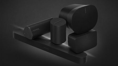 A collage of Sonos speakers and soundbars stacked on top of each other on a smoky black background