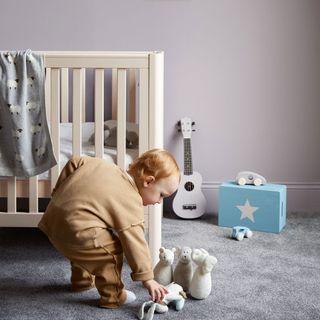 Warm grey nursery with cot and child playing with toys