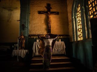 Photo featuring woman in a church before life-sized crucifix, from Sony World Photography Awards 2023