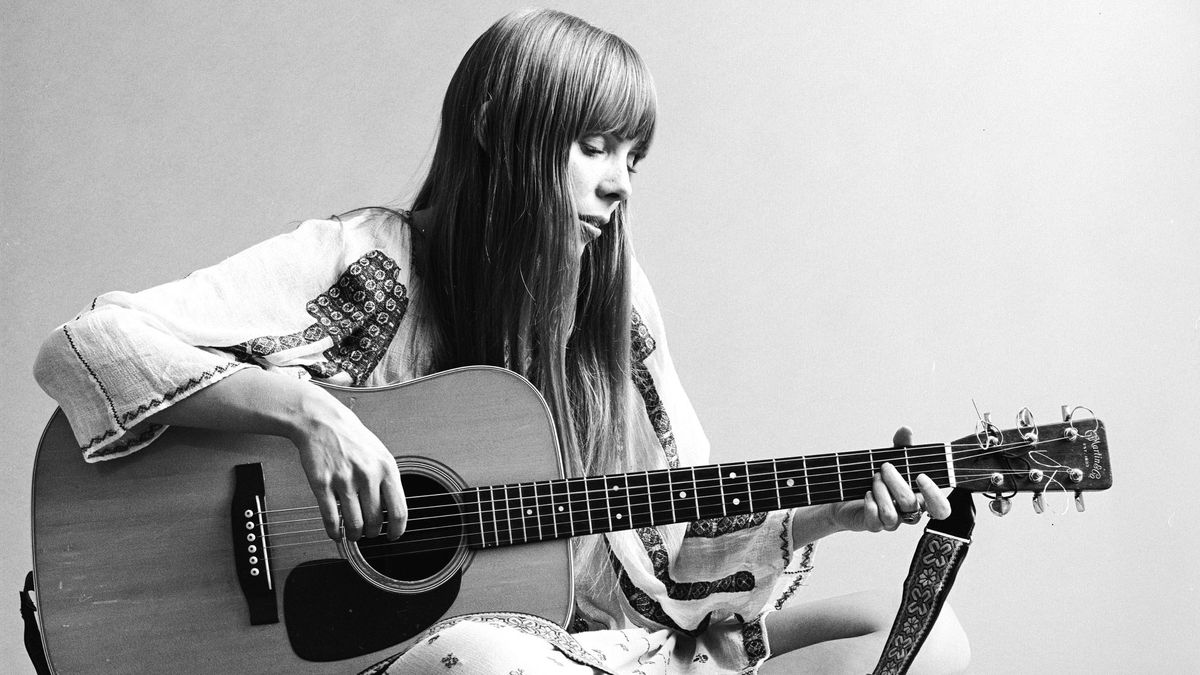 Portrait of Canadian musician Joni Mitchell seated on the floor playing acoustic guitar, November 1968.