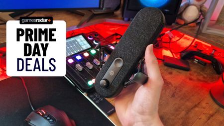 Steel Series Alias mic being held by a reviewer in front of a rodecaster duo. To the left there's a Prime Day deals stamp